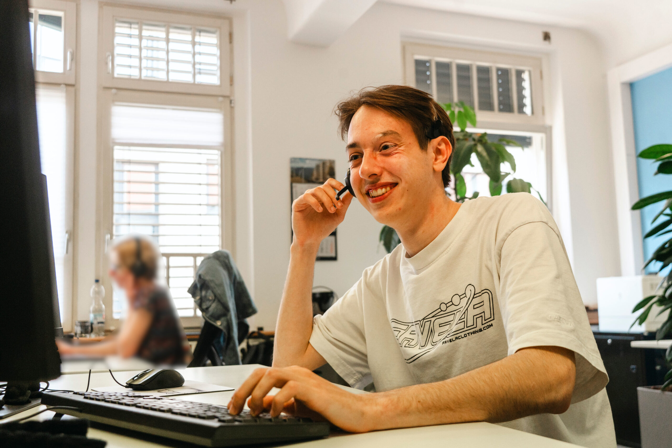 4M-Mitarbeiter mit Headset am Schreibtisch