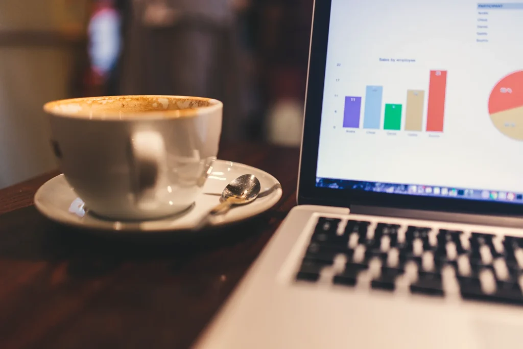 Laptop mit Diagrammen, daneben Kaffeetasse