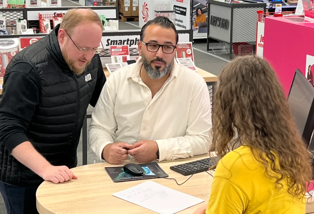 4M-Mitarbeiter steht Sales Promoter im Beratungsgespräch mit Kundin zur Seite
